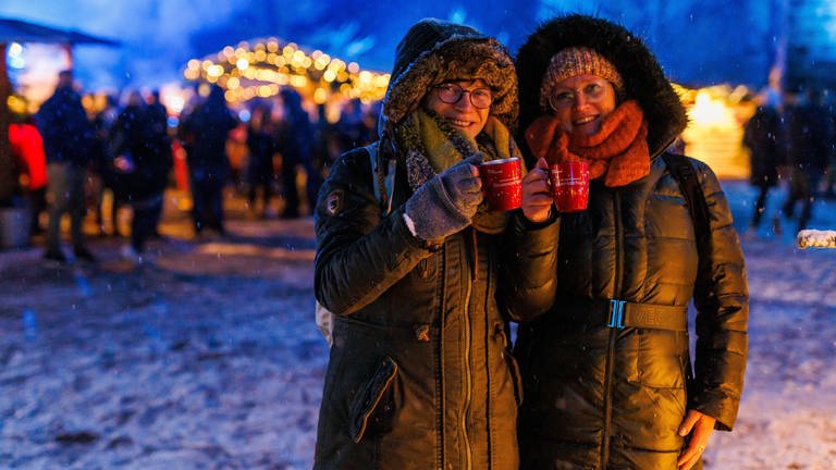 Zwei Frauen stehen mit zwei Tassen Glühwein in der Hand auf dem Weihnachtsmarkt. (Foto: dpa Bildfunk, picture alliance/dpa | Philipp von Ditfurth)
