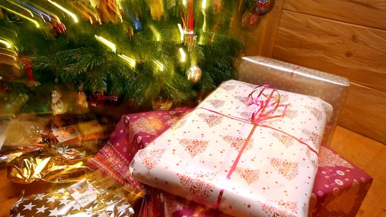 Weihnachtsgeschenke liegen unter einem geschmücktem Christbaum. (Foto: dpa Bildfunk, Picture Alliance)