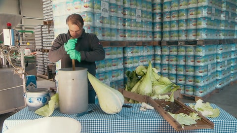 Jörg Kimmich steht vor vielen Dosen mit Sauerkraut und stampft frisches Filderkraut in einem großen Topf. (Foto: SWR)