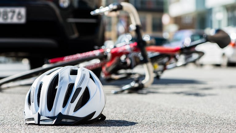 Fahrrad und Helm liegen nach einem Unfall mit einem Auto auf dem Straße.  (Foto: Colourbox)