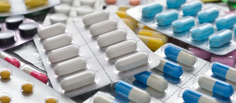 Verschiedene Blister mit weißen und bunten Tabletten und Kapseln liegen auf einem Tisch. Helfen Probiotika wirklich der Gesundheit? (Foto: Colourbox, Colourbox6724640)