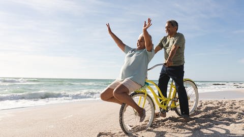 Senioren am Strand mit einem Fahrrade und sehr guter Laune (Foto: picture-alliance / Reportdienste, picture alliance / Zoonar | Channel Partners)