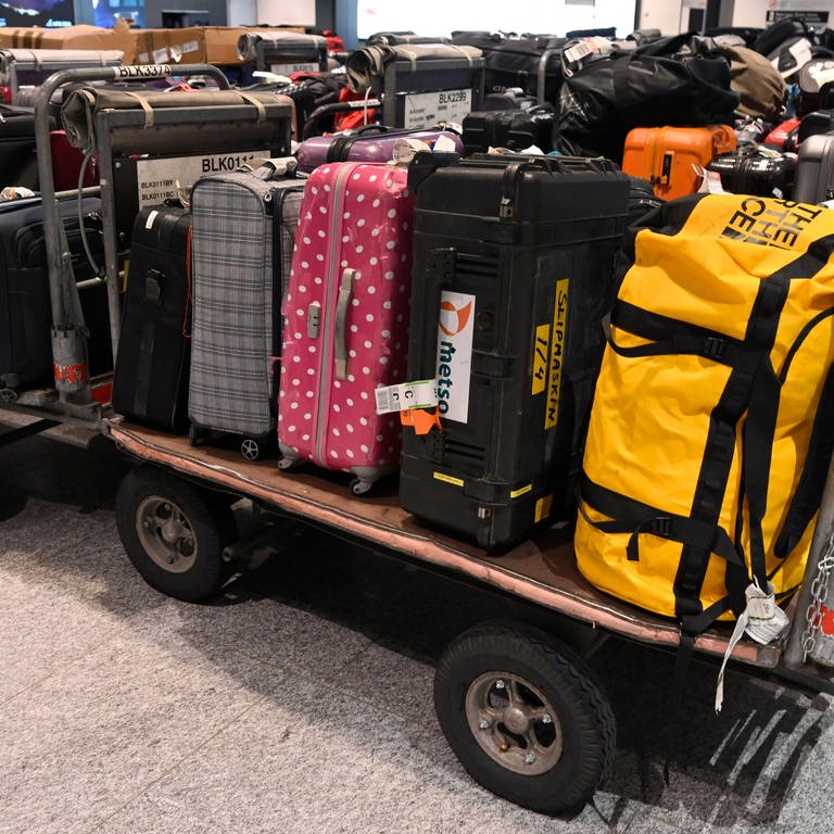 Gepäck kann auch ohne Urlauber allein schon mal vorfahren: Viele Koffer liegen auf offenen Transportwagen.  (Foto: IMAGO, IMAGO / Pius Koller)