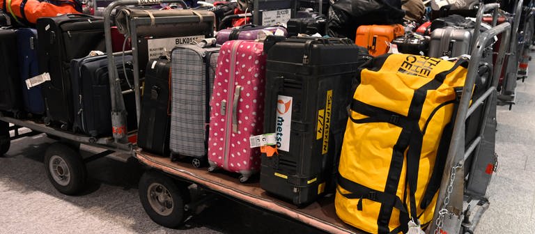 Gepäck kann auch ohne Urlauber allein schon mal vorfahren: Viele Koffer liegen auf offenen Transportwagen.  (Foto: IMAGO, IMAGO / Pius Koller)