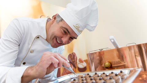 Ein Chocolatier mit Kochmütze von Lindt verziert Pralinen. Marktcheck checkt Lindt - wie gut ist die Schokolade? (Foto: dpa Bildfunk, Picture Alliance)