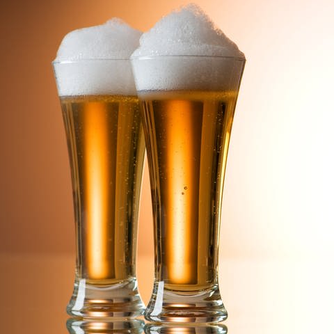 Zwei Gläser Bier stehen nebeneinander auf einem Tisch. Chemie hat einiges mit der Bildung von Bierschaum zu tun. (Foto: Colourbox)