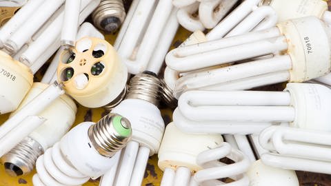 Kaputte Energiesparlampen liegen auf einem gelben Untergrund. Wie entsorgt man alte LEDs, Glühbirnen, Halogenlampen? Was darf in den Restmüll? Wo gibt es Sammelstellen? (Foto: Adobe Stock I papi8888)