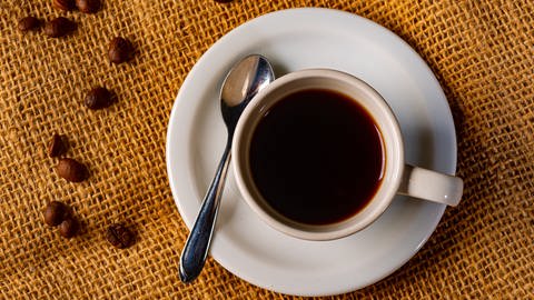 Tasse mit schwarzem Kaffee, dekoriert mit Kaffeebohnen (Foto: Colourbox)