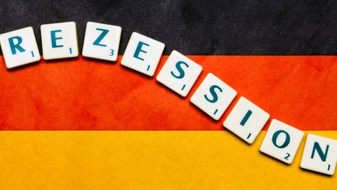 Auf einer Deutschlandfahne befinden sich die Scrabble-Buchstaben für das Wort Rezession. (Foto: dpa Bildfunk, picture-alliance/ dpa)