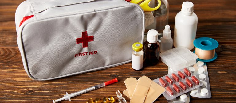 Auf einem Tisch liegt eine Erstehilfetasche mit verschiedenen Medikamenten und Pflastern. (Foto: Colourbox)