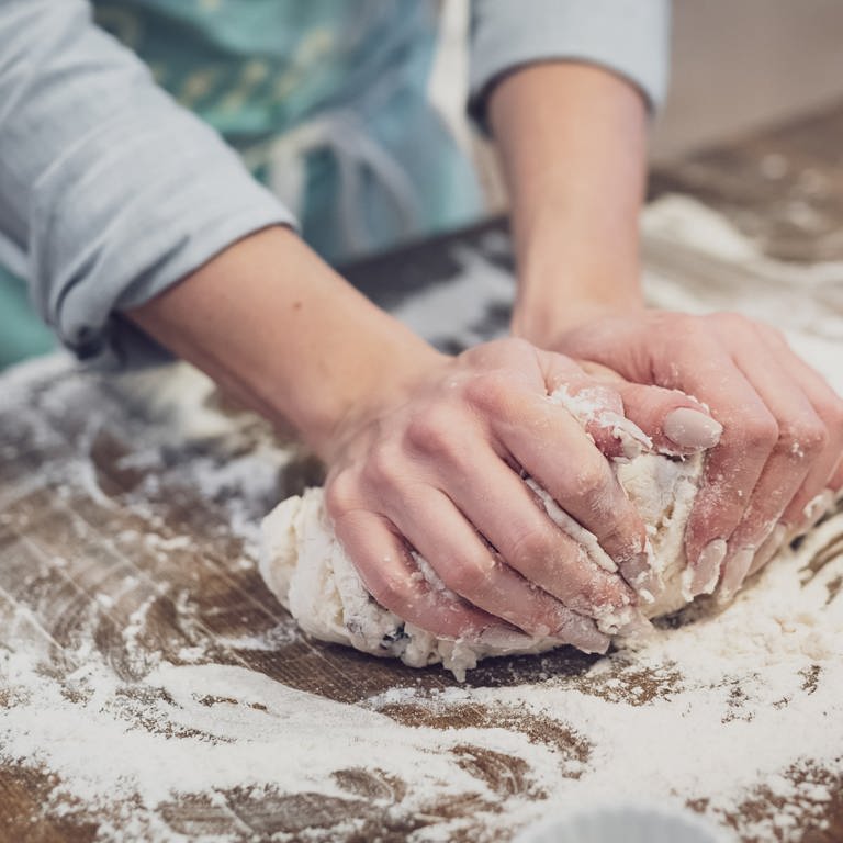 Zwei Hände kneten auf einer Arbeitsplatte Teig mit viel Mehl. Brotbackmischungen im Test: Welche Backmischung ist die beste? (Foto: Unsplash / Theme Photos)