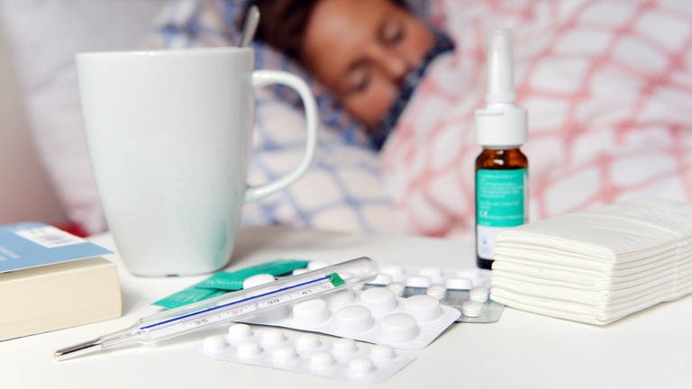Frau liegt krank im Bett, davor Medikamente, Tee, Nasenspray und Fieberthermometer auf dem Nachttisch. Was hilft bei akuter und chronischer Rhinosinusitis?  (Foto: dpa Bildfunk, Picture Alliance)