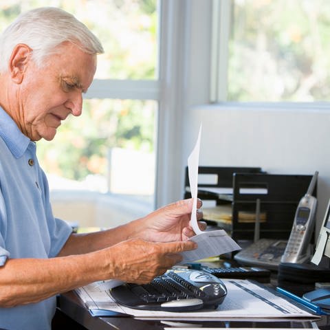 Ein älterer Mann blickt auf ein Blatt Papier (Foto: Colourbox)