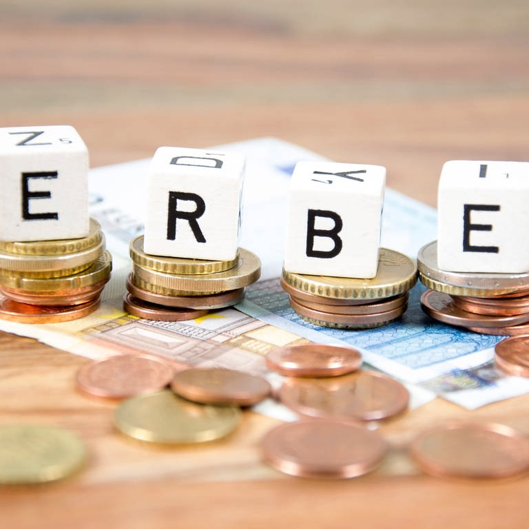 Mit Buchstaben-Würfeln wird das Wort "Erbe" gelegt. Die Würfel liegen auf Geldscheinen und Münzen. (Foto: Colourbox)