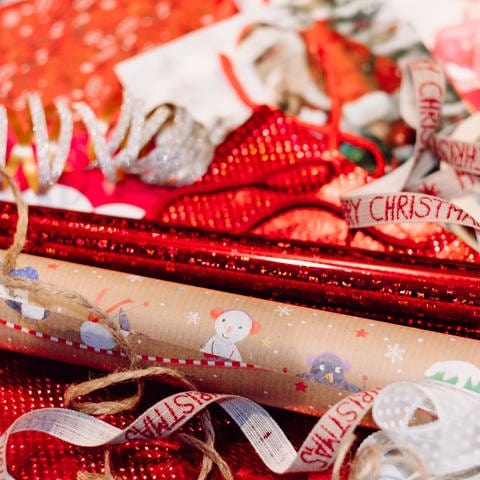 Geschenkpapier zu Weihnachten in rot und Pappe. Geschenkbänder in silber, rot und als Kordel. (Foto: Unsplash/Freestocks)