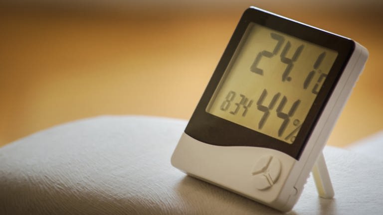 Ein Hygrometer steht auf einem Sofa und zeigt die Wärme und Luftfeuchtigkeit an (Foto: Kaffeebart/unsplash.com)