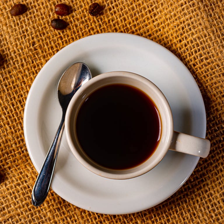 Tasse mit schwarzem Kaffee, dekoriert mit Kaffeebohnen (Foto: Colourbox)