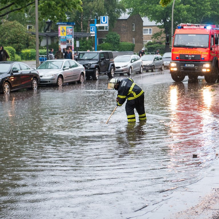 Eine Feuerwehrfrau steht auf einer von starkem Regen überfluteten Straße. (Foto: dpa Bildfunk, picture alliance/dpa | Daniel Bockwoldt)