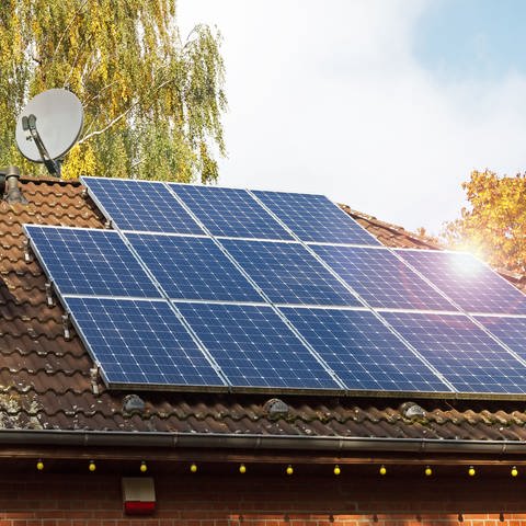 Auf dem Dach eines Einfamilienhauses ist eine Photovoltaikanlage installiert. Mehrere Solarpanel decken das Dach ab. (Foto: Adobe Stock)