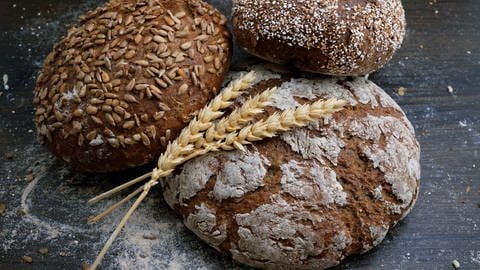 Drei Brote auf einem Brett angerichtet. In Brot stecken einige Kohlenhydrate. (Foto: Wesual Click via Unsplash)