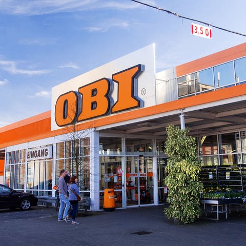 Eine Filiale der Baumarktkette Obi: Vor dem Eingang stehen Pflanzen, oben am Gebäude hängt das orangene Logo von Obi. (Foto: dpa Bildfunk, picture alliance / dpa | Jens Büttner)