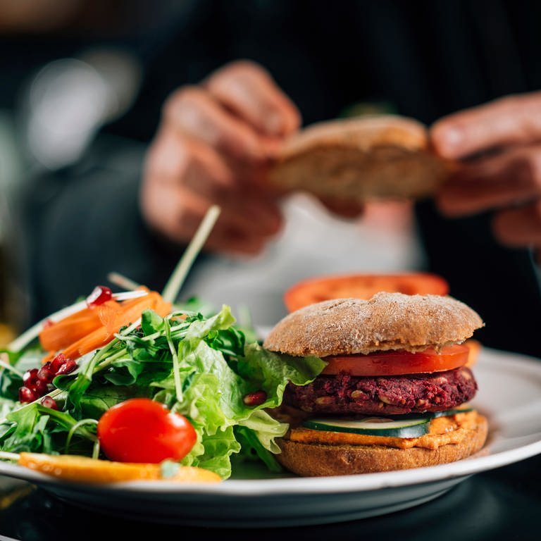 Ein Koch bereitet vegane Burger in einer Restaurantküche zu. (Foto: Adobe Stock, Adobe Stock/Microgen)