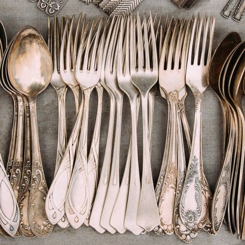 Mehrere Silbergabeln und -löffel liegen nebeneinander auf einem Tisch. (Foto: Adobe Stock, Adobe Stock/Grigory Bruev)