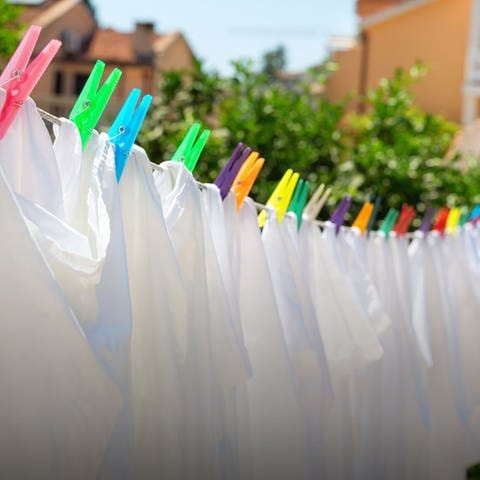 weiße Wäsche hängt mit bunten Wäscheklammern an einer Wäscheleine