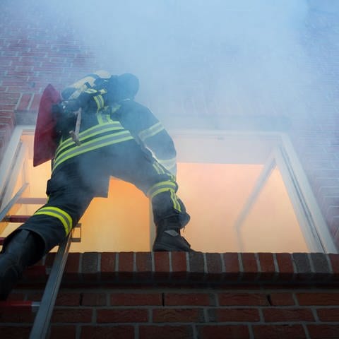 brennendes Haus mit Feuerwehrmann (Foto: Adobe Stock, Christian Schwier)