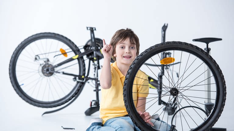 Kind beim Wechseln und Flicken eines platten Fahrradreifens