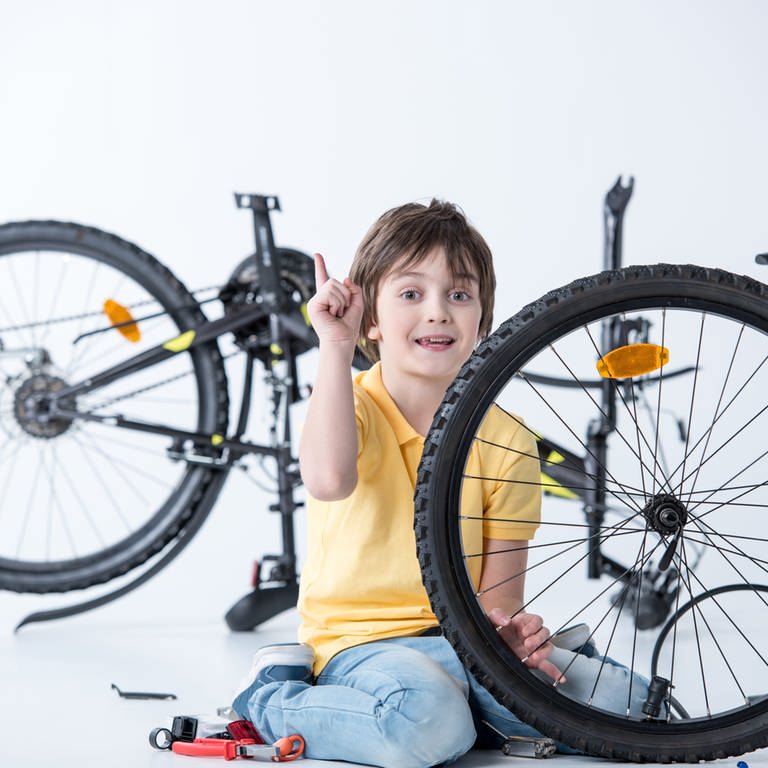 Kind beim Wechseln und Flicken eines platten Fahrradreifens