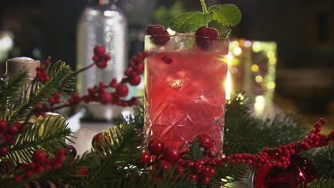 Ein dekoriertes Glas mit dem Cocktail Raspbirdy in einer weihnachtlichen Umgebung. (Foto: SWR)