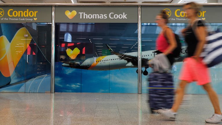 Passagiere gehen neben einem großen Werbeschild von Thomas Cook am Flughafen von Palma de Mallorca. (Foto: dpa Bildfunk, Clara Margais)