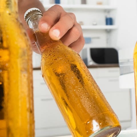 Person nimmt gekühltes gelbfarbenes Getränk aus einem Kühlschrank.