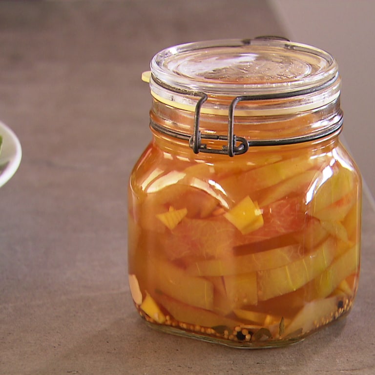 Gelbe Stückchen in orangefarbenem, klaren Sud mit Senfkörnern in Weckglas. Auch Melonenschalen sind essbar: Hier ein Rezept zum Einlegen.