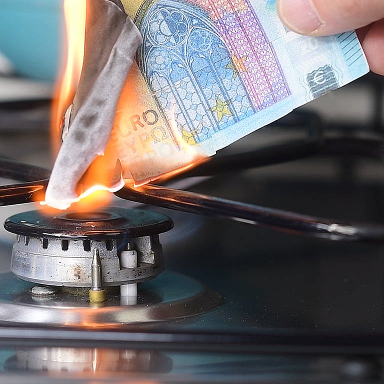 Hand hält brennende Euro-Geldscheine an Gasflamme. Welche Rechte haben Verbraucher angesichts steigender Gas- und Strompreise gegenüber den Versorgern?