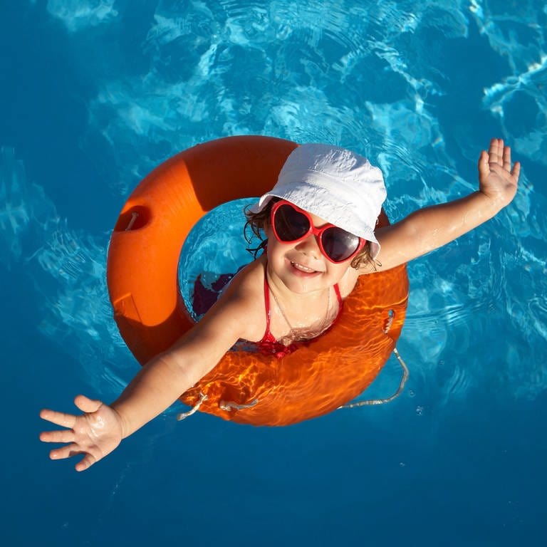 Kind in einem Schwimmreifen mit Hut und Sonnenbrille
