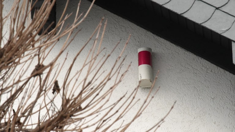 Eine Alarmanlagen-Attrappe kann potenzielle Einbrecher abschrecken und ist eine kostengünstige Alternative zur Installation einer echten Alarmanlage. Eine Alarmanlage-Attrappe wurde an der Außenwand eines Hauses installiert. (Foto: SWR)