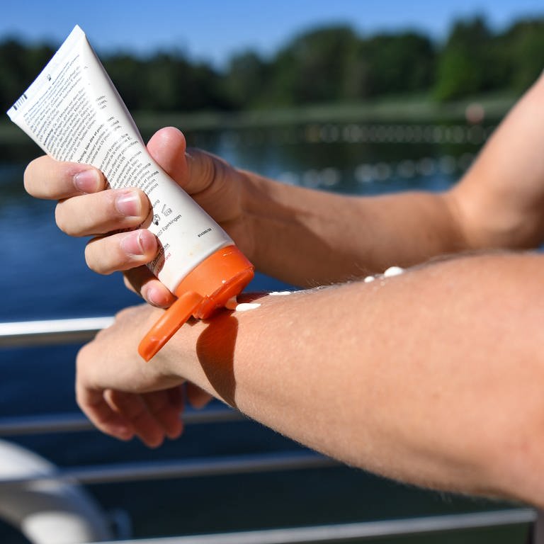 Auf einem Arm wird im Frühjahr Sonnencreme oder Sonnenmilch aufgetragen.