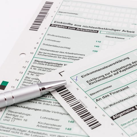Auf einem Tisch liegt Steuererklärungsformular für 2022. Ein Kugelschreiber zeigt auf die Überschrift: Einkommenssteuer.