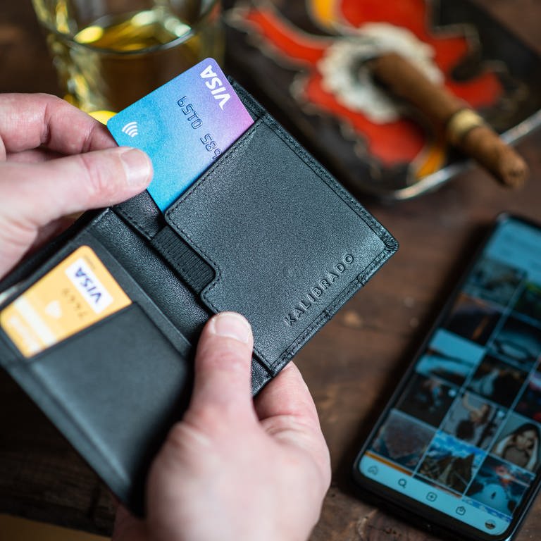 Mann zieht Kreditkarte aus einem Portemonnaie