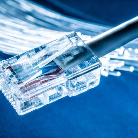 Glasfaserm, davor ein LAN-Kabel. Glasfaservertrag an der Haustür: Verbraucher beschweren sich über Vertriebsmethoden.