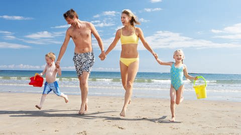 Familie am Strand - Reiseversicherung bringt Schutz im Urlaub 