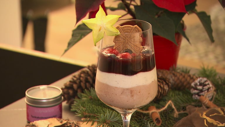 Ein Nachtisch ist in einem Weinglas angerichtet. Im Hintergrund ist weihnachtliche Dekoration. (Foto: SWR)