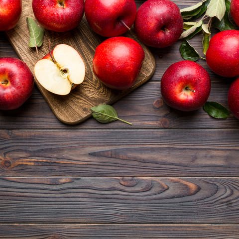 Wunderschöne rote Äpfel liegen auf einem Holztisch. Was hat es mit speziellen Sorten wie Aldiamo, Magic Star und Cameo auf sich?