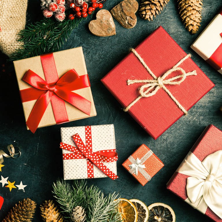 Verpackte Weihnachtsgeschenke liegen auf einer Platte. Welche Rechte haben Verbraucher, wenn sie Waren umtauschen wollen? Wie steht es um Gewährleistung und Garantie? Kann ich Geschenke zurückverlangen? (Foto: Adobe Stock, Adobe Stock | Cookie Studio | George Dolgikh)