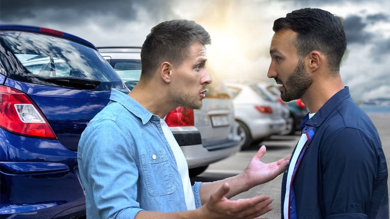 Zwei Männer streiten vor geparkten Autos. Welche Strafen gibt es bei Fahrerflucht? Und kann ich Unfallflucht begehen, ohne es zu merken?