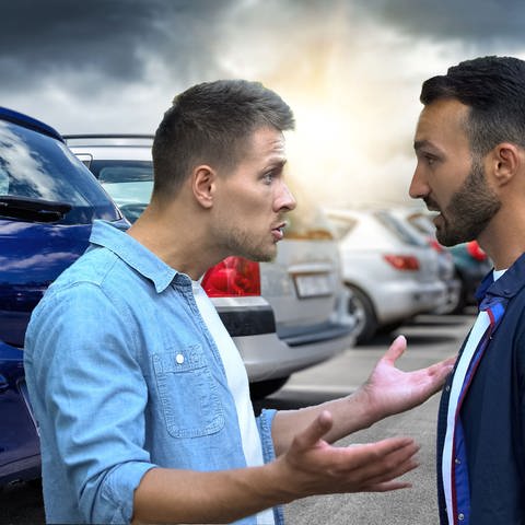 Zwei Männer streiten vor geparkten Autos. Welche Strafen gibt es bei Fahrerflucht? Und kann ich Unfallflucht begehen, ohne es zu merken? (Foto: Colourbox)