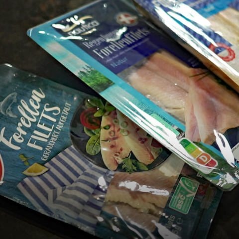 Verschiedene Forellen-Produkte liegen auf dem Boden. Geräucherte Forelle ist beliebt bei den Deutschen. Wie gut sind die Produkte im Handel und lohnt sich der Griff zum Bio-Fisch? 