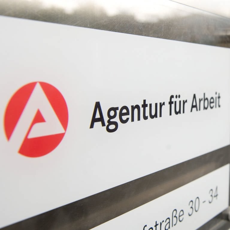 Ein Mann geht hinter dem Schild der Agentur für Arbeit in Stuttgart zum Eingang.